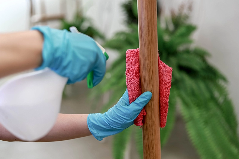 Curățarea galeriei din lemn cu o lavetă și spray în cadrul întreținerii casnice